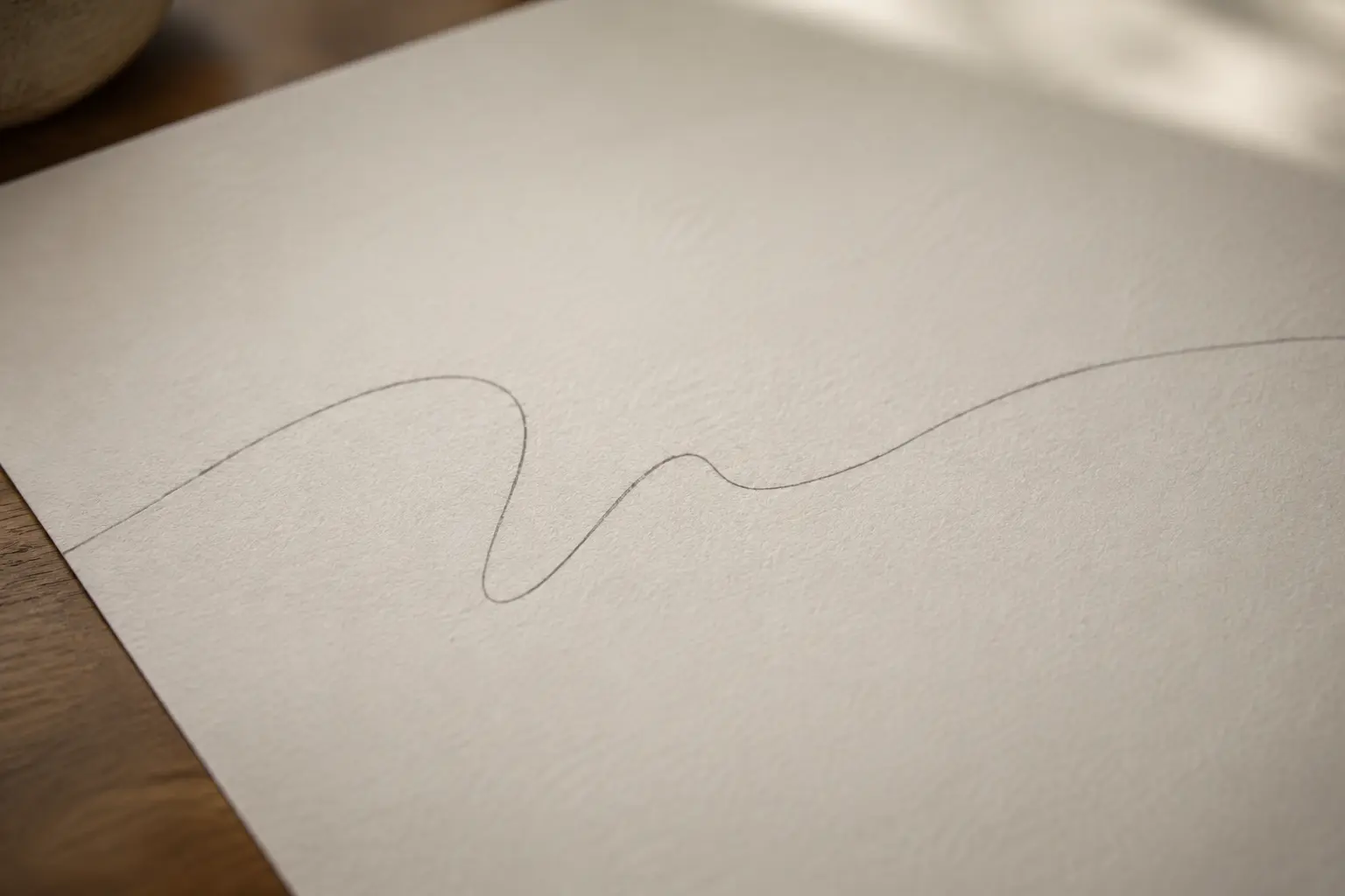 A single abstract graphite line crossing warm cream paper